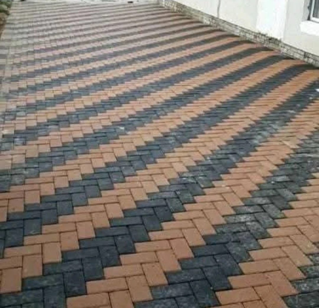 Herringbone paving with charcoal zigzag bands running through buff pavers.