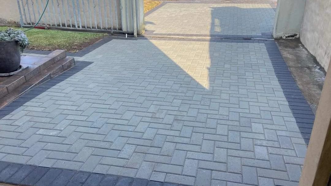 Grey herringbone driveway paving with a charcoal border running to the gate.