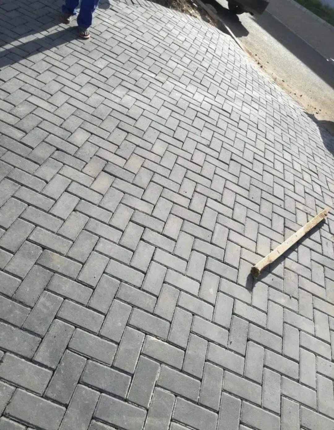 Grey herringbone pavers freshly laid on a sloping driveway.