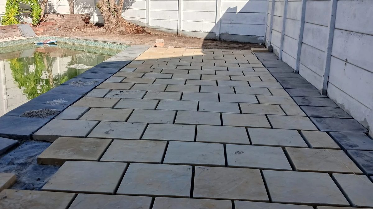 Pool paving in buff textured slabs, with charcoal slabs along the pool edge.