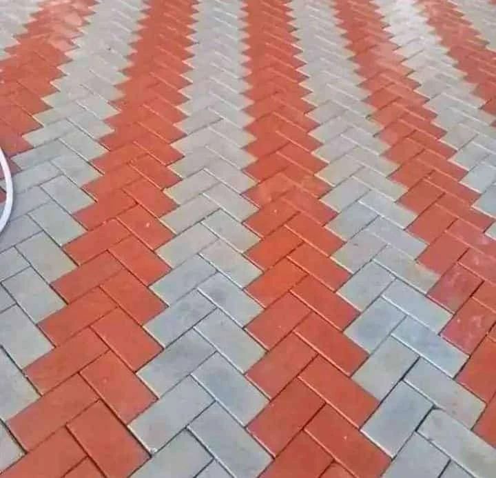 Red and grey pavers laid in herringbone, forming chevron stripes.
