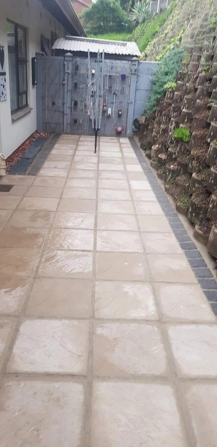 Side passage paved in sandstone-look slabs with a charcoal paver border.