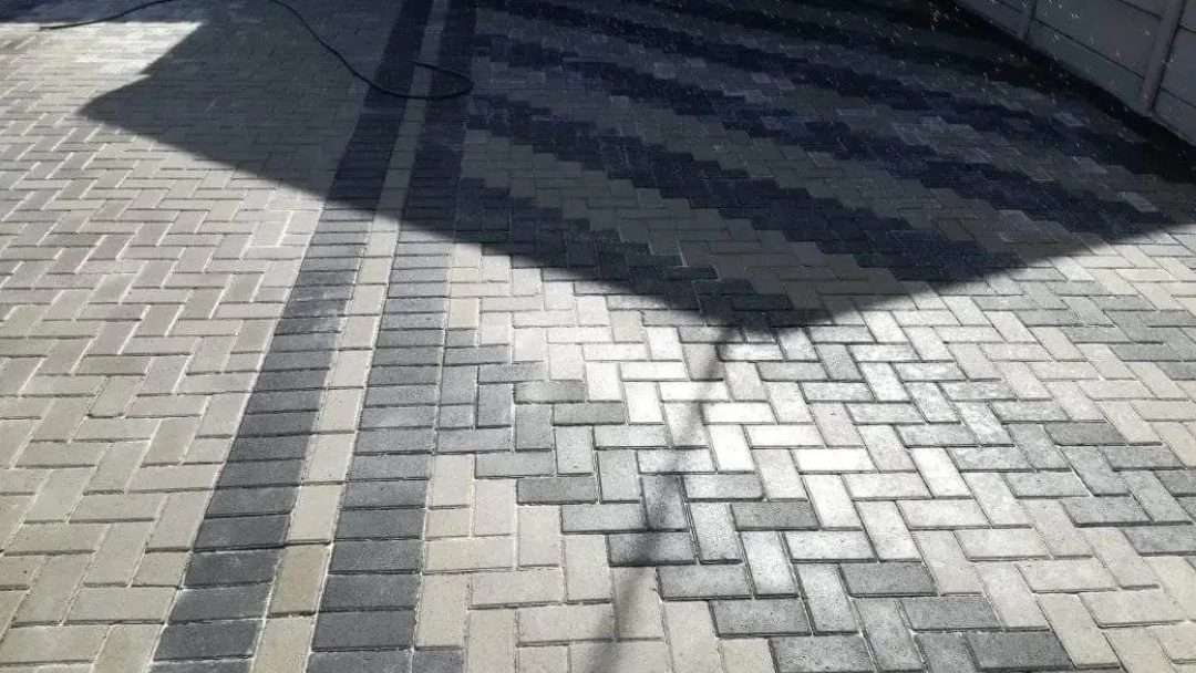 Two-tone paving pattern: grey herringbone with a charcoal stripe and diamond inlay.